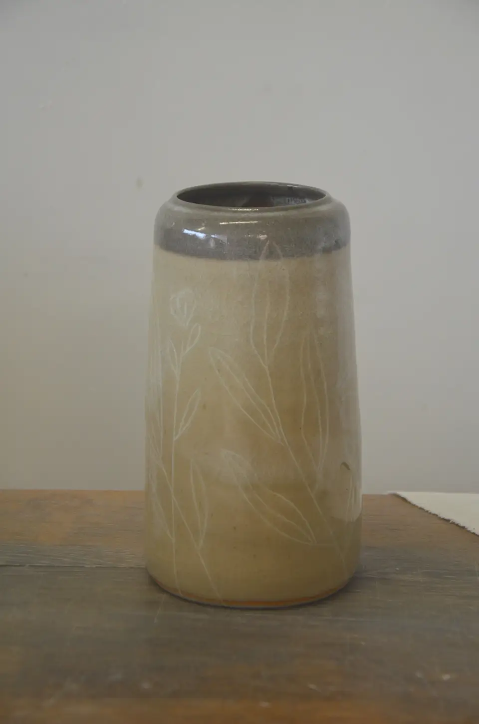 Vase beige à col gris, décor de feuillages blancs.