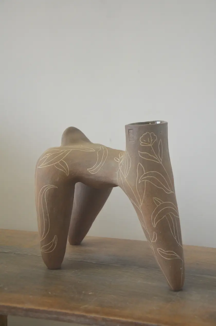 Pièce brune à quatre pieds ornée de feuillages blancs, vue de trois quarts, ouverture au premier plan.
